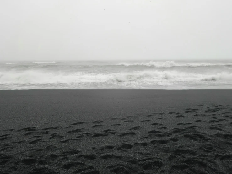 the ocean and waves in the distance with black sand