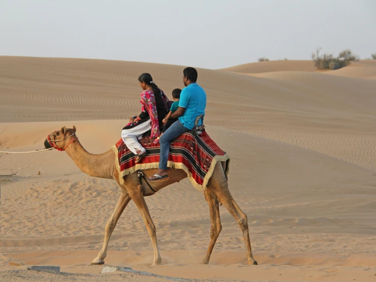 a couple sitting on top of a camel in the desert