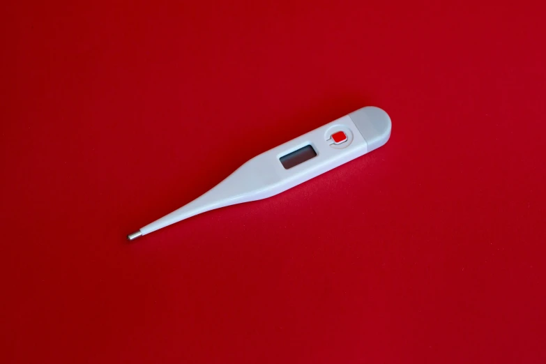 a close up of a white electric toothbrush on a red table