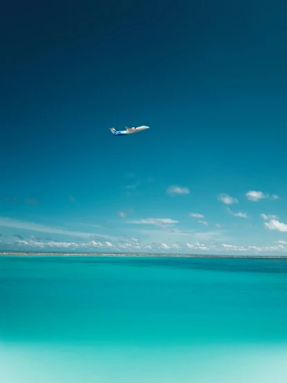 there is a plane flying over the blue ocean