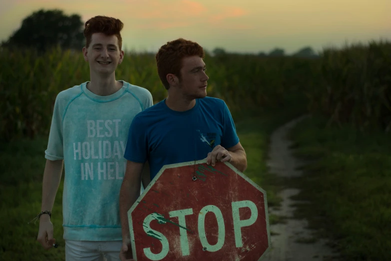 two men walking up a road together holding a stop sign