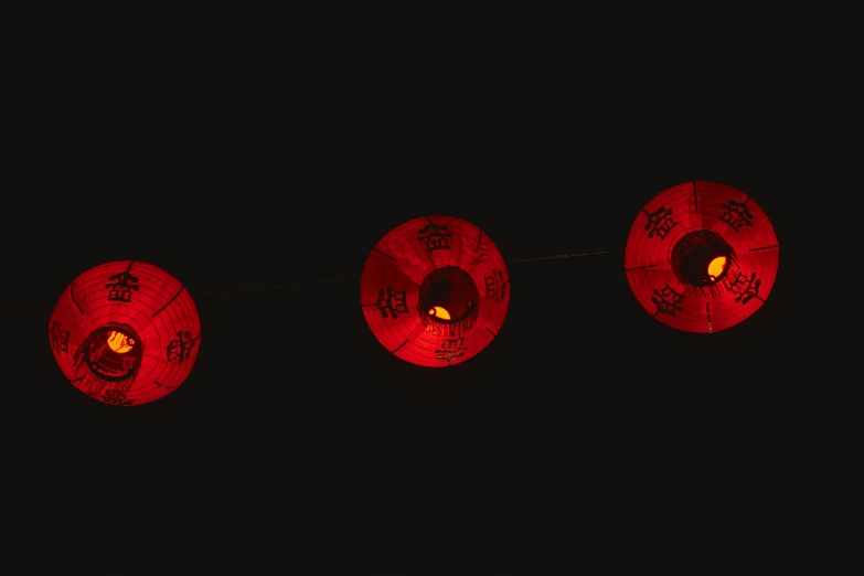three chinese lanterns are lit up in the dark