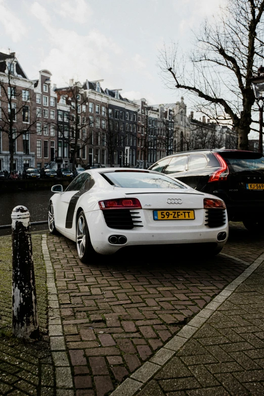 some very pretty white cars parked by a building