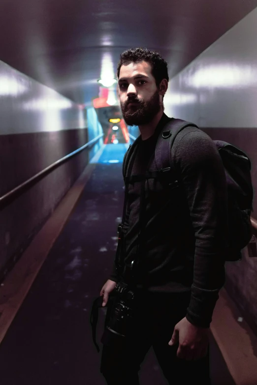 a man wearing a backpack and carrying a camera is standing in an elevator