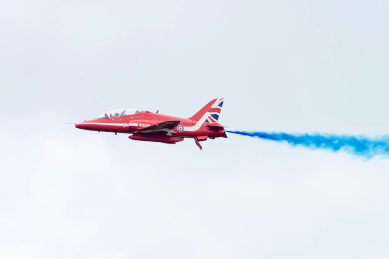 a red jet leaving a trail of blue smoke