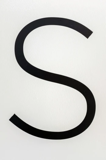 the letter s is etched into the surface of a white wall