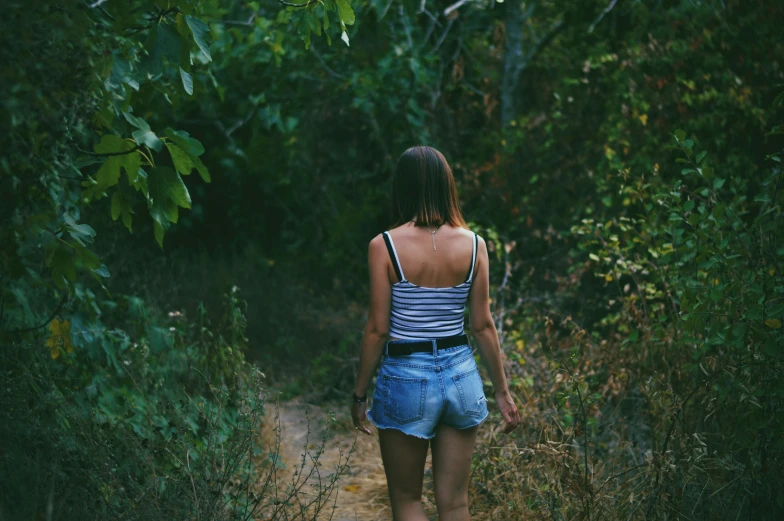 woman standing on dirt path near trees in open area