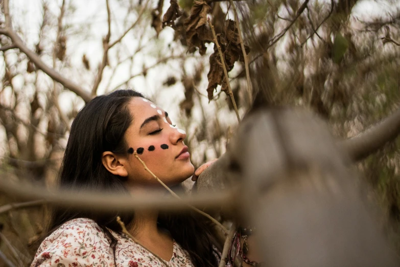 a woman with nose markings and in the woods