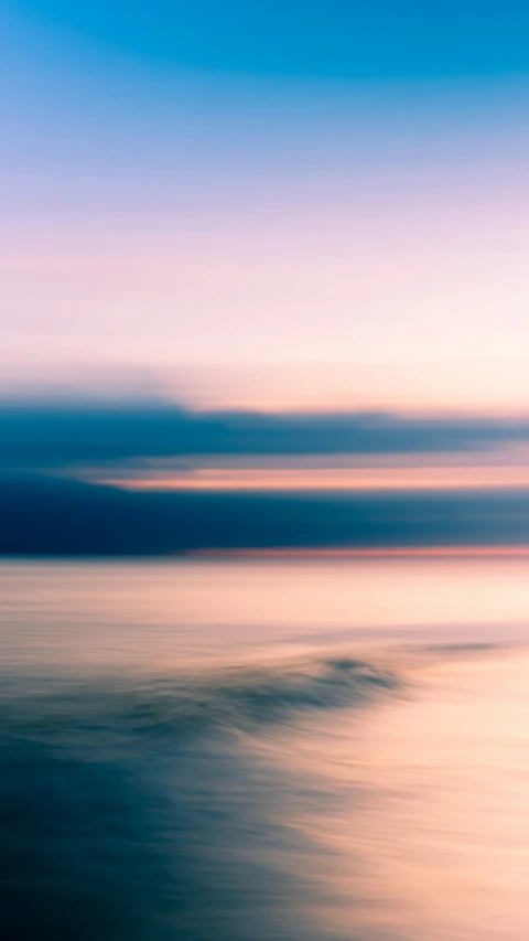 blurred pograph of ocean in pink and blue with horizon in background