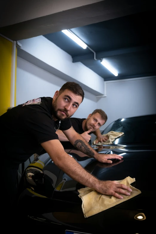 two men in an automobile shop waxing their cars