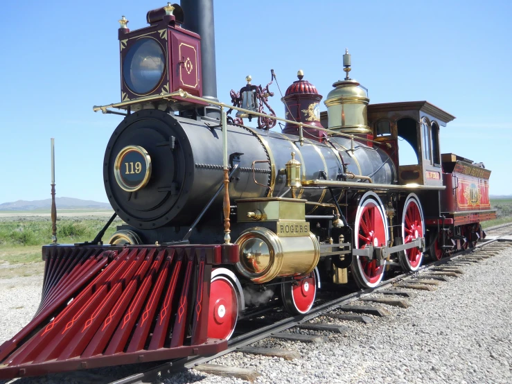 a train traveling down tracks on gravel next to a mountain