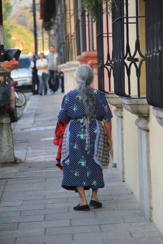 a woman in a patterned robe walks down the street