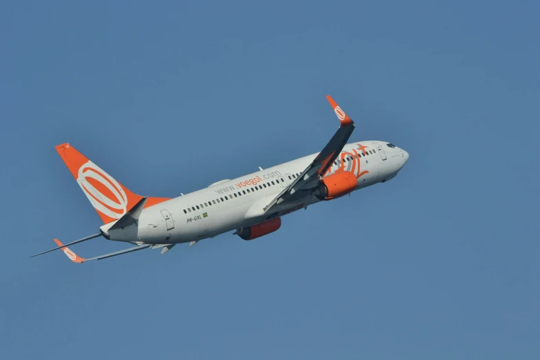 an airplane with orange trim and lettering in the air