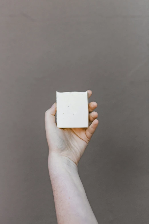 a woman holding up a square of soap