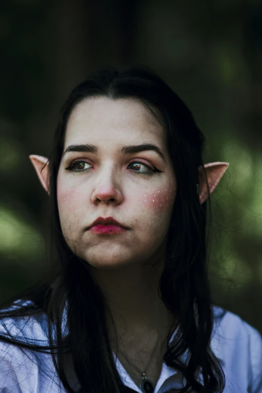 a woman in white shirt with dark hair wearing an elf ears