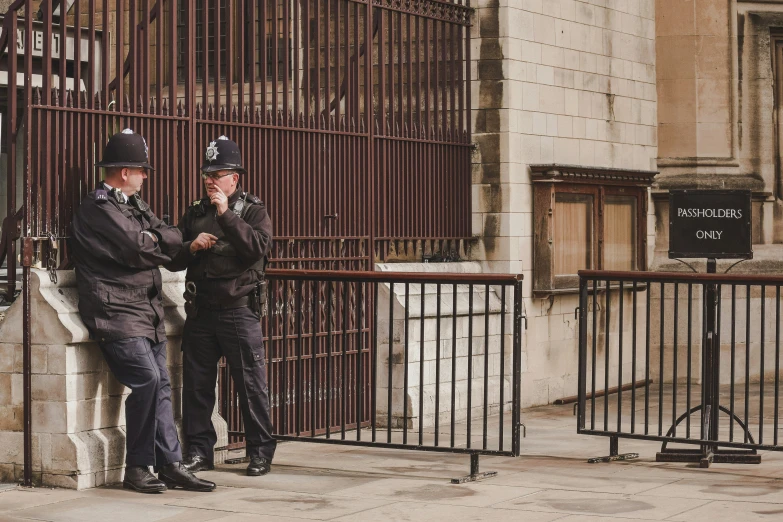 two policemen standing in front of an iron gate