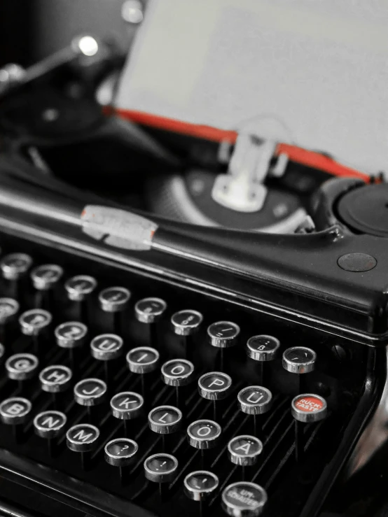 an old typewriter with red ribbon and ons sitting on the desk