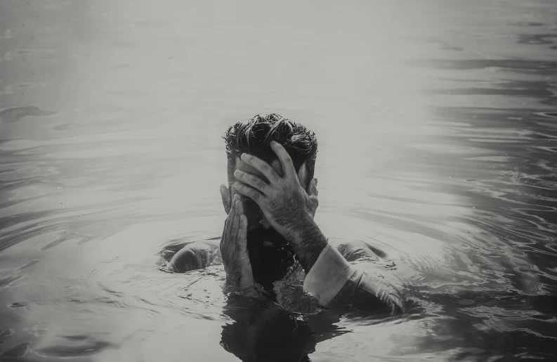 a person in the water with their hands over their face