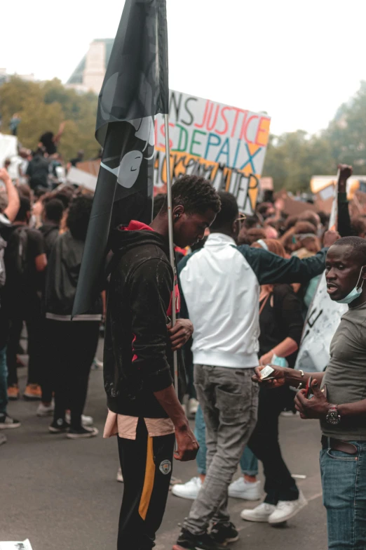 a group of people standing around one another holding a sign