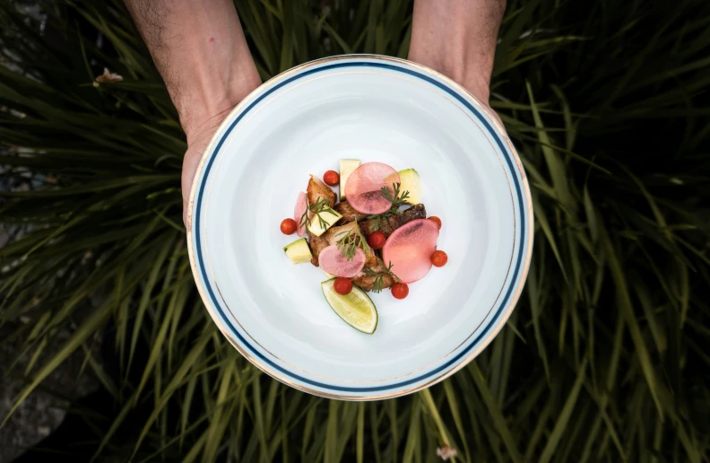 someone holding a small white plate with some fruit on it