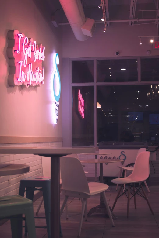 there are two tables that have chairs and a neon sign