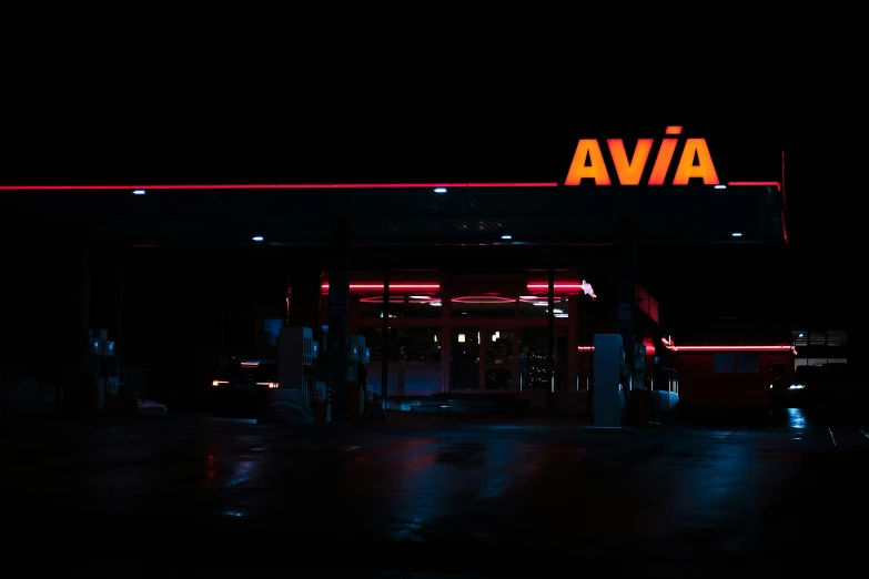 a gas station with neon lights on the top