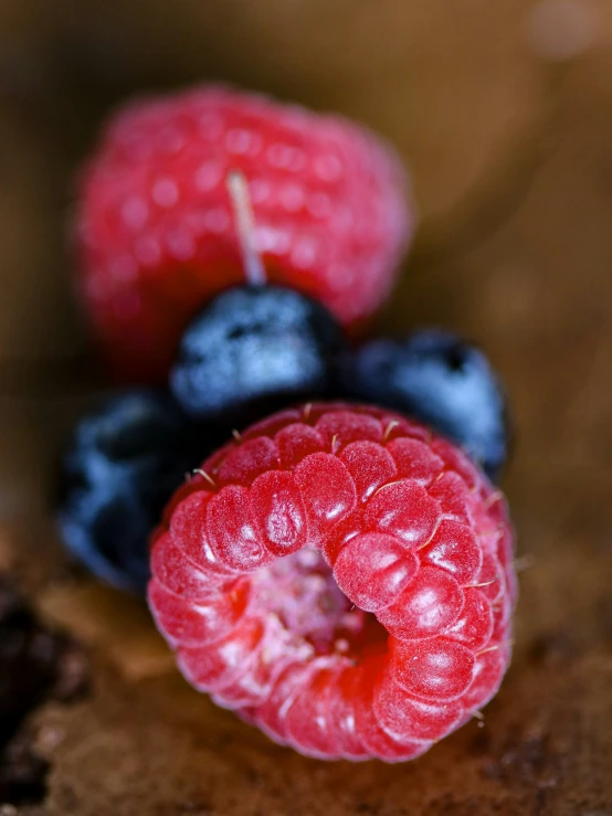 raspberries on a piece of wood with blueberries