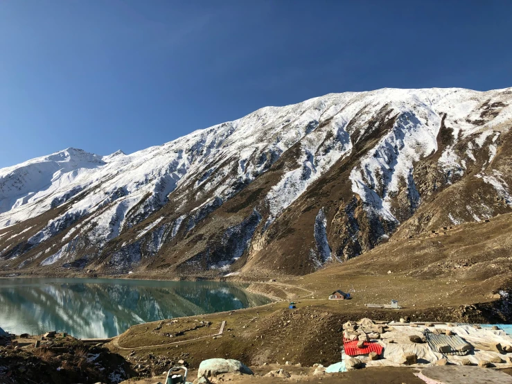 snow covered mountains surround lake with tents on land