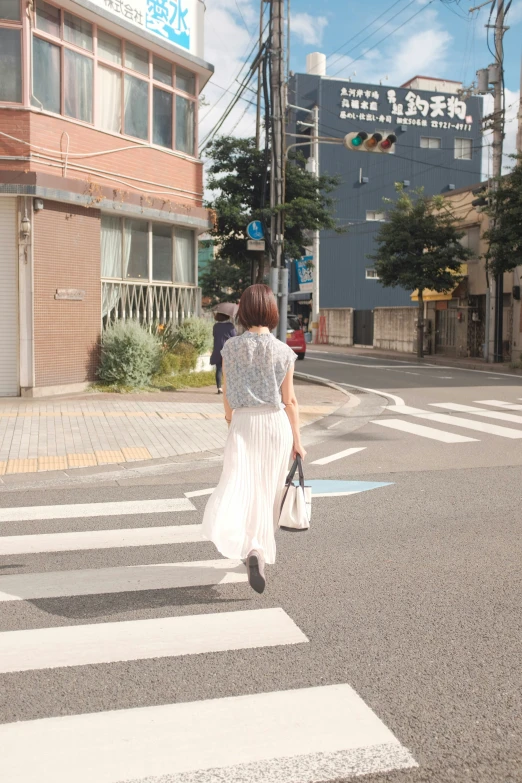 the woman is crossing the street and she's carrying a handbag