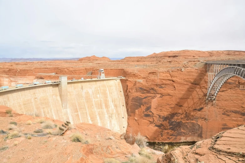 a large dam in the middle of desert with a bridge above