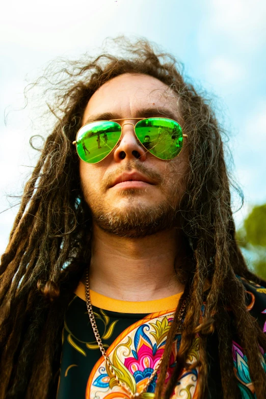 a man with long hair and green sunglasses looking off into the distance