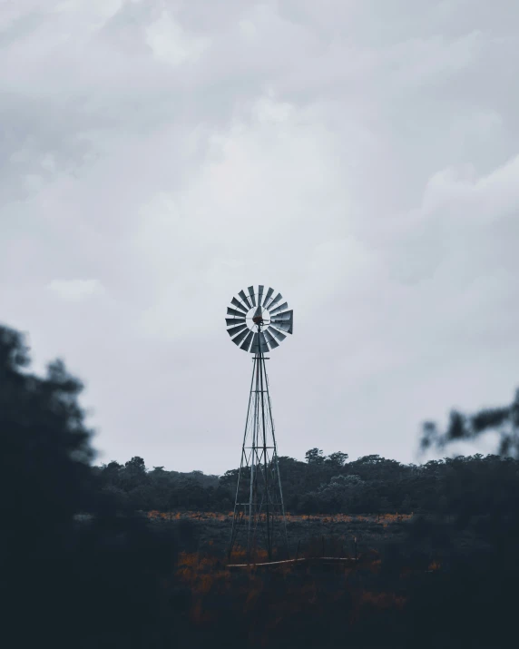 a windmill on top of a hill in front of some clouds