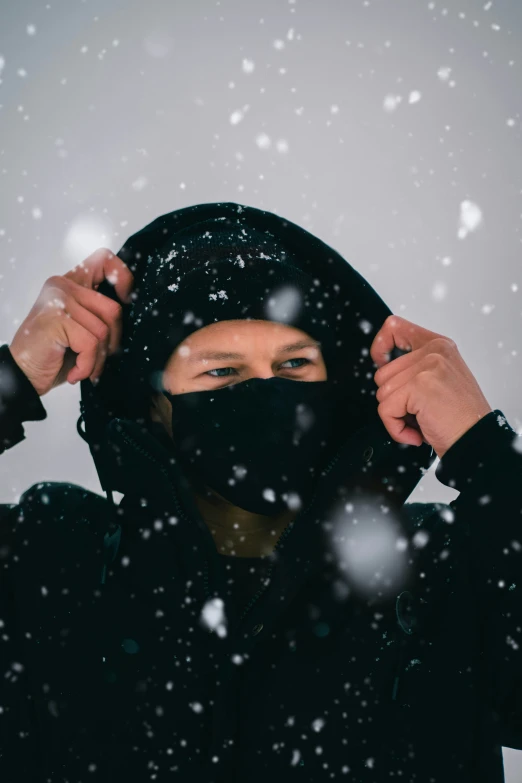 a man is wearing a face mask and a hoodie