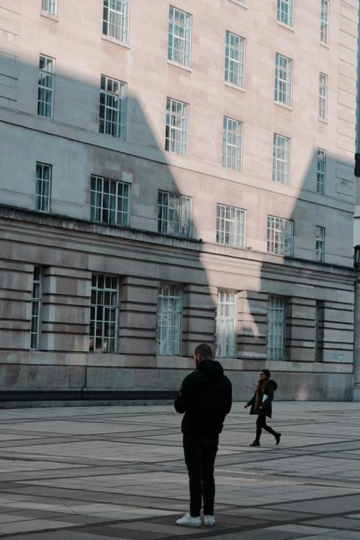 two people are walking on the street in front of the building