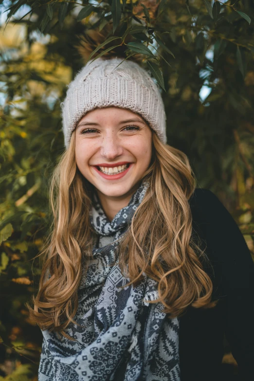 a girl smiling, standing in front of a tree