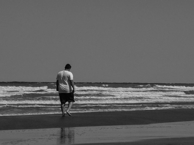 a man is walking along the beach near the water