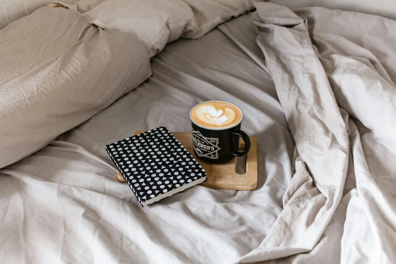 a coffee cup sitting on top of a bed with a napkin and napkin