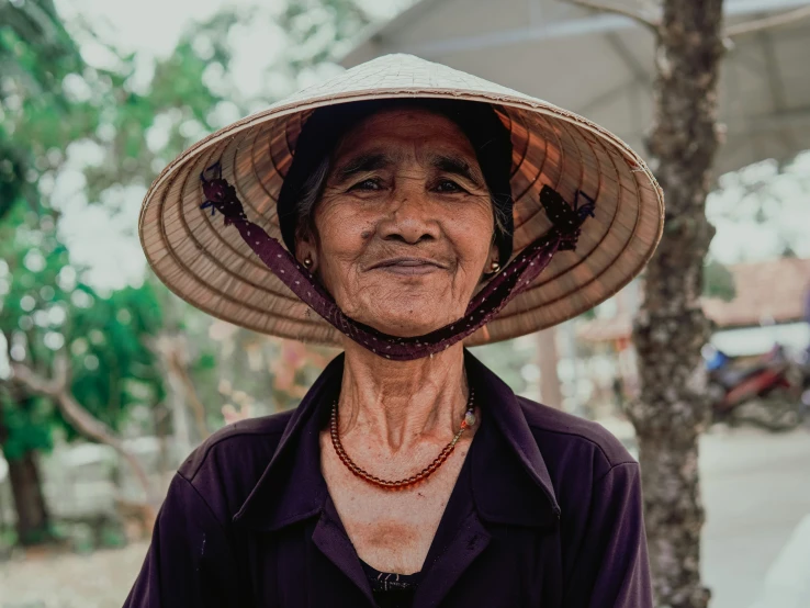 an elderly asian woman wearing a hat and purple shirt