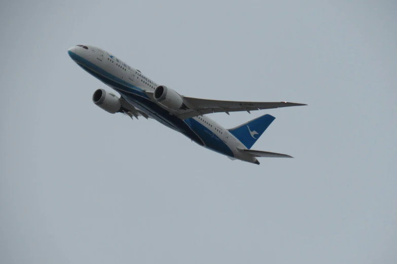 a blue and white plane flying in the sky
