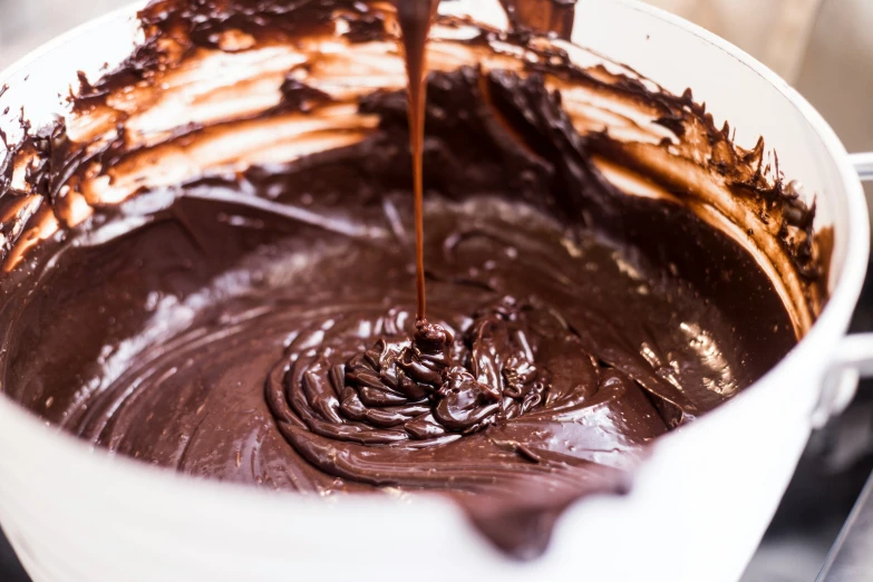 melted chocolate in white bowl being stirred with whiskers