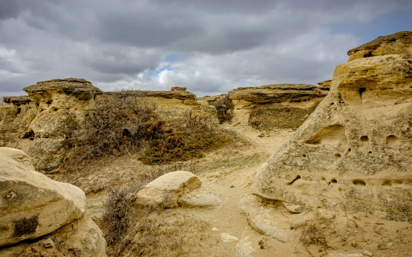 rocky mountains sit among sand and gravel beneath a cloudy sky