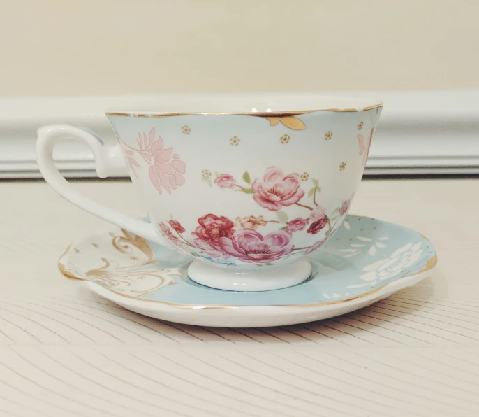 a cup and saucer on top of a white table