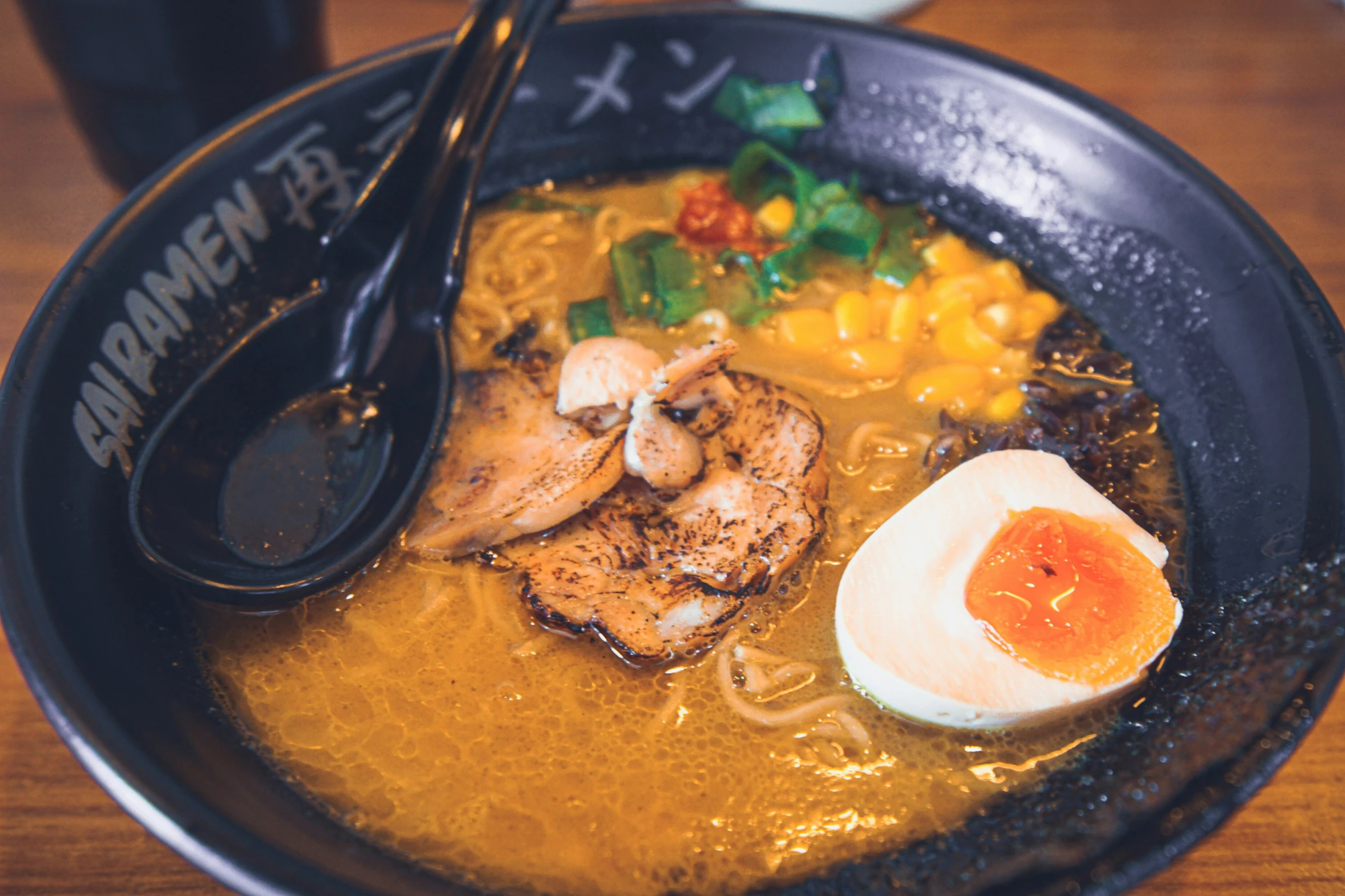 the bowl is full of soup with chicken, eggs and shrimp