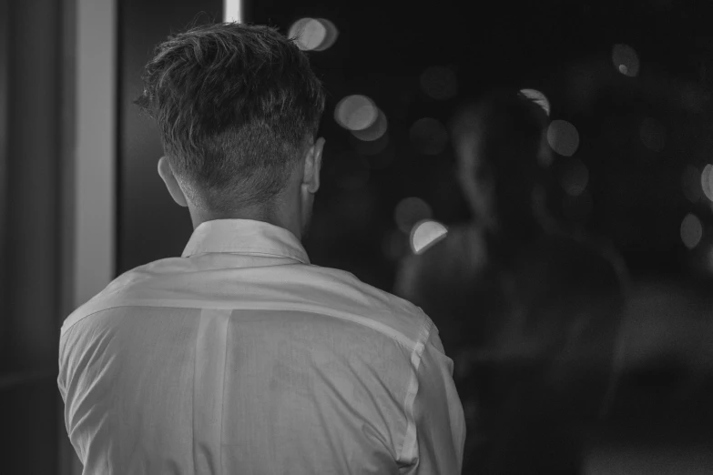 a man looking into a mirror with lots of lights in the background