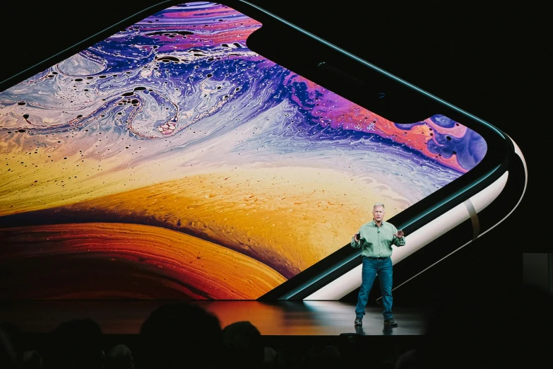 a man on stage with an iphone xr