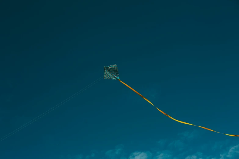 an orange kite against a blue sky with some clouds