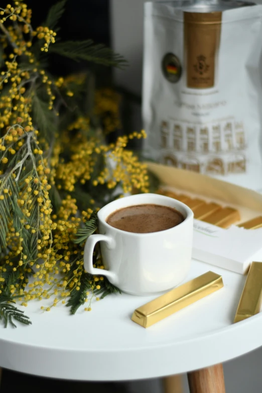 a white coffee cup and gold plate with yellow flowers on it