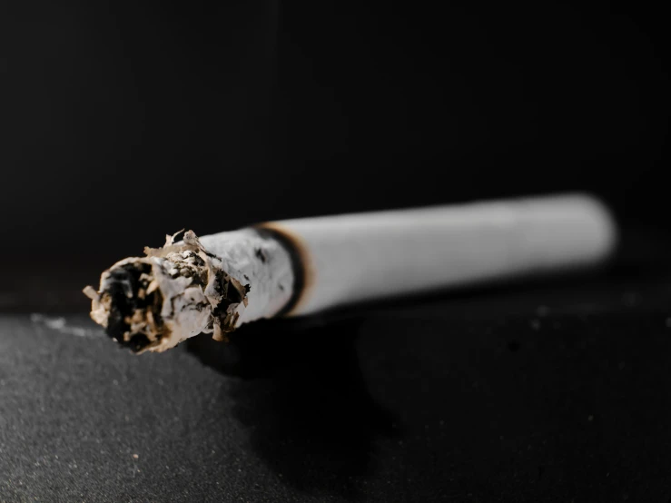 a cigarette with the end partially opened on a black background