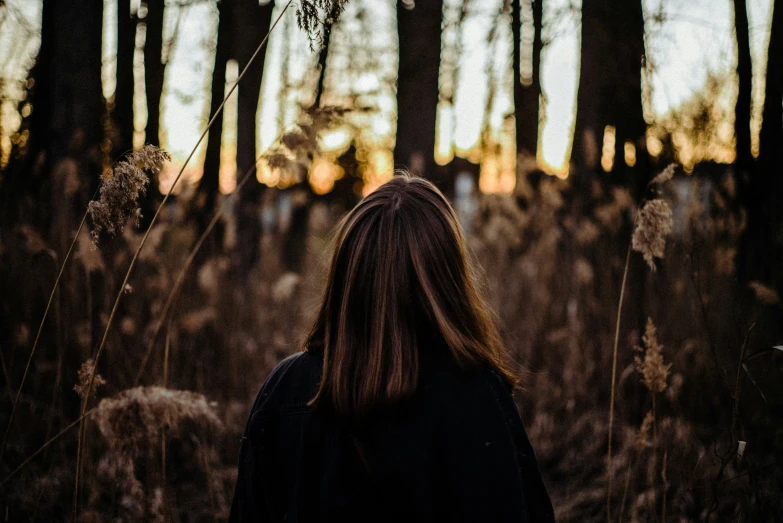 a person in black coat standing in a forest