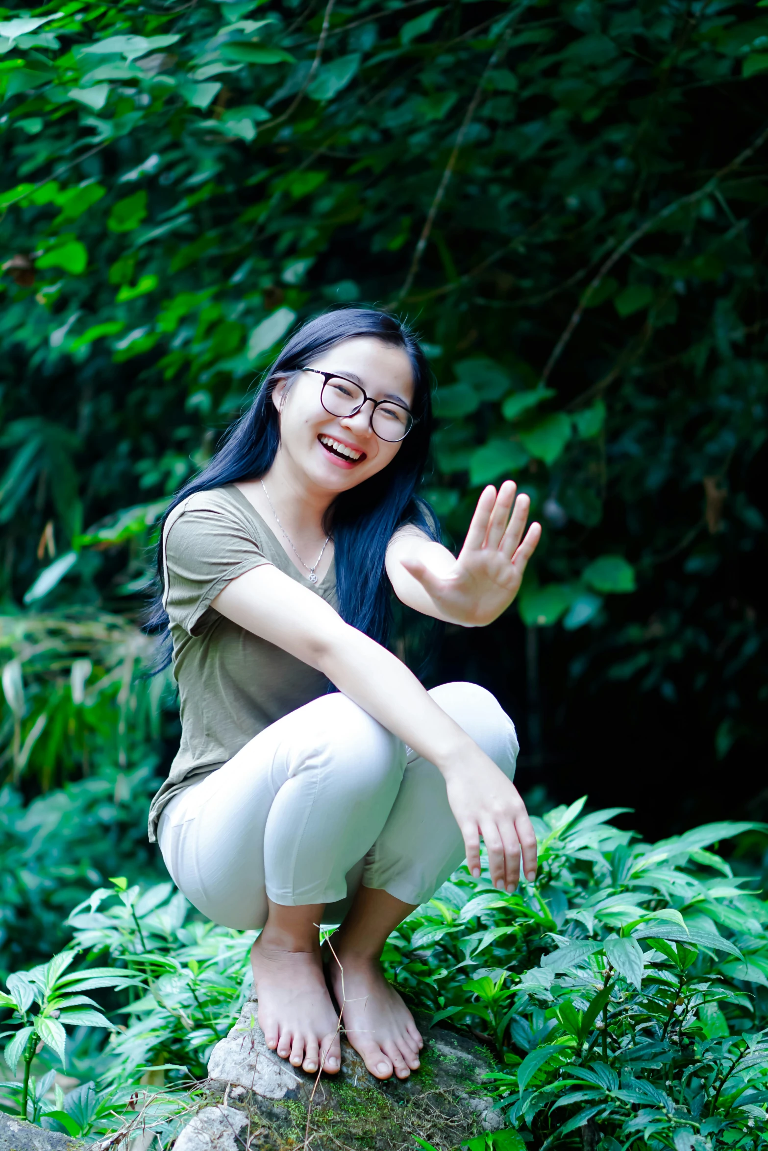 the girl smiles brightly while squatting in the green jungle